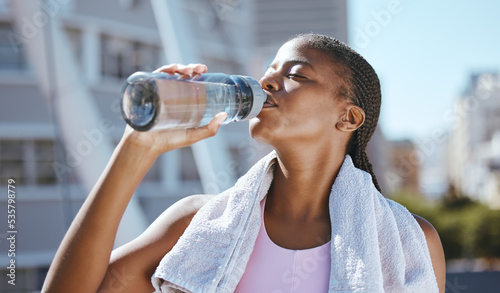 Fitness, exercise and black woman drinking water after running, training and cardio workout in summer. Tired, runner and thirsty African girl with healthy liquid for hydration, energy and wellness photo