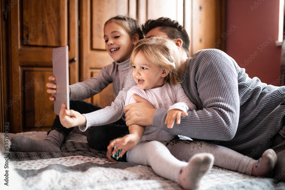 Fototapeta premium Father playing and joking with his daughters in bedroom Cozy time wih father Father daughter time