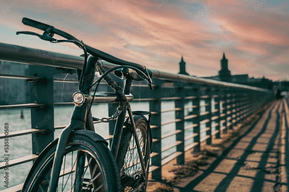 Fototapeta premium Closeup shot of an old bicycle on the bridge at sunset in Berlin, Germany