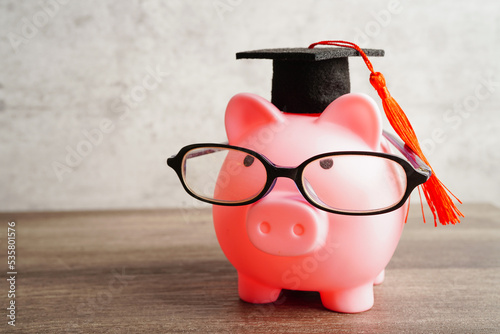 Pigging bank wearing eyeglass with coins and calculator saving bank education concept. photo