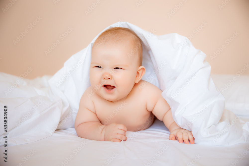 baby boy in a diaper is lying on a white sheet, covered with a blanket in the bedroom on the bed baby boy in a diaper is lying on a white sheet, covered with a blanket in the bedroom on the bed