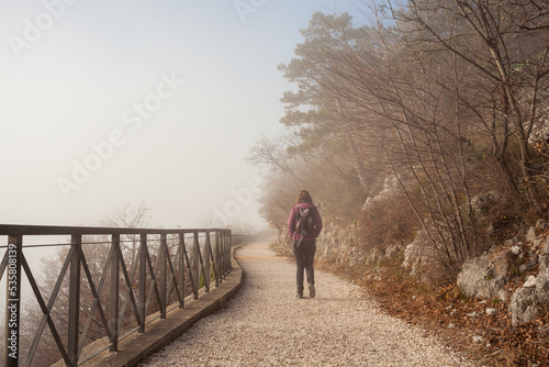 Woman walking alone on rural misty path