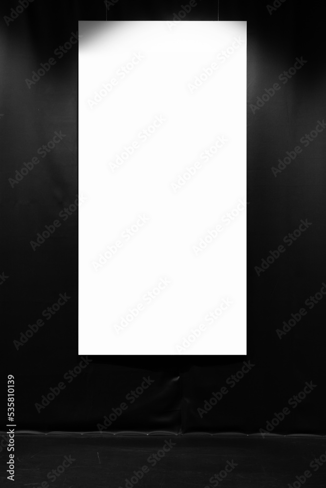 Blank vertical poster hangs on a black wall Blank vertical poster hangs on a black wall