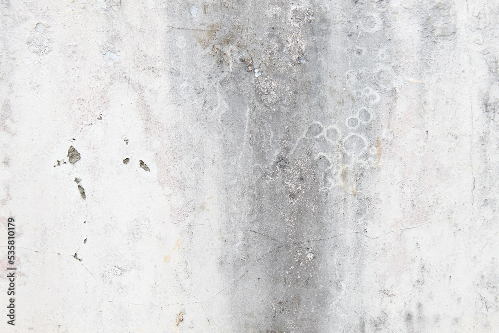 Fototapeta premium A weathered concrete wall with cracks and peeling paint, showing signs of age and decay.