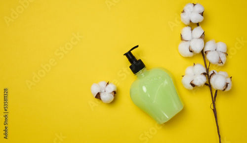 Transparent plastic bottle with green liquid on a yellow background