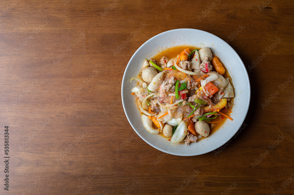 Top view of spicy Seafood Salad on a wooden table, Thai spicy food, Spicy salad, Copy space.