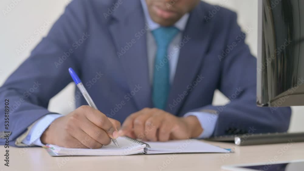 Close Up of Young African Businessman Writing on Notebook Close Up of Young African Businessman Writing on Notebook
