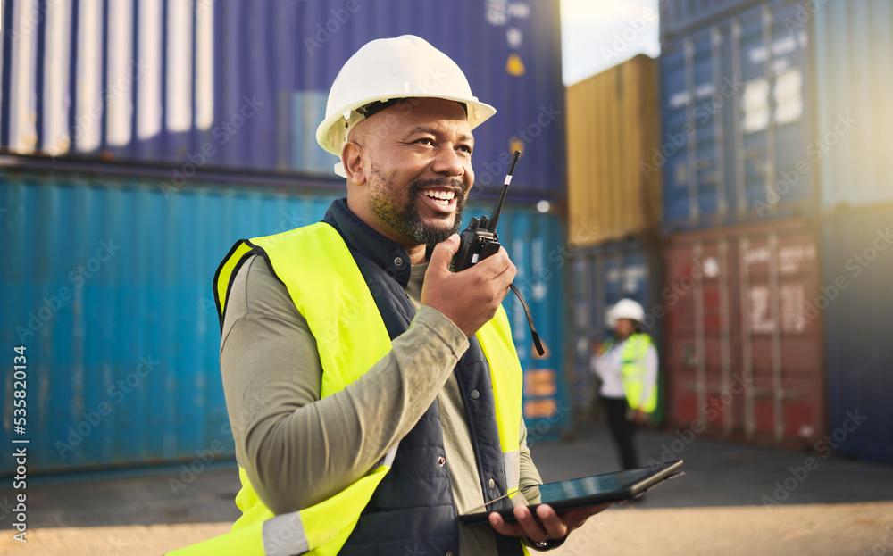 Logistics, radio and a black man in shipping container yard with tablet. Industrial cargo area, happy transport worker talking on walkie talkie in safety gear and working for global freight industry. - obrazy, fototapety, plakaty 