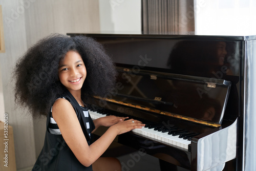 Smile teenage girl happy to playing piano in free time for hobby in living room of house