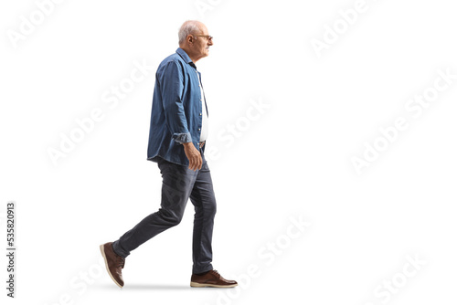 Full length profile shot of a mature man in a denim shirt walking