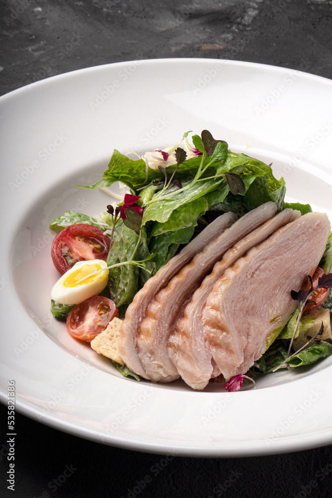 Salad with chicken fillet and vegetables on a white plate