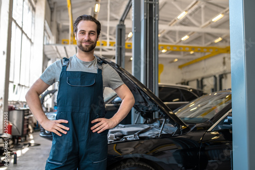 Contented mechanic posing for the camera in the workplace