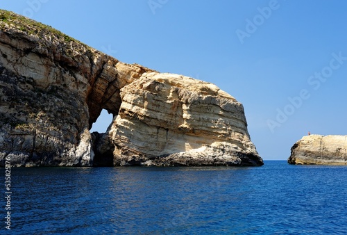 Scenic rocks with a hole near Gozo island on Malta, on bright summer day