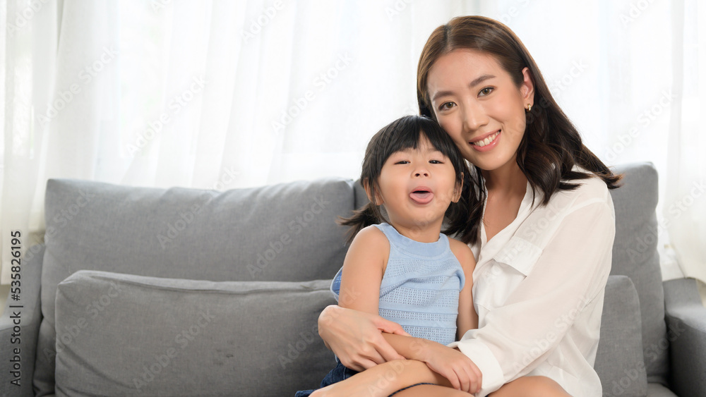 Portrait of Asian mom and little girl  smiling on sofa at home
