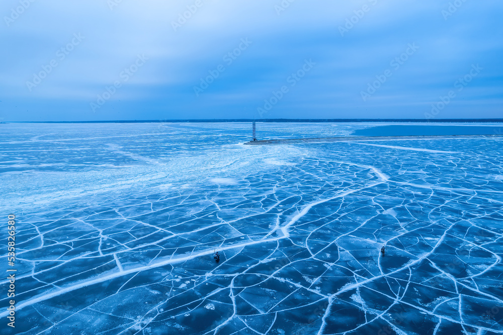 aerial view of a lonely lighthouse in the frozen sea. Frozen blue ice in cracks
