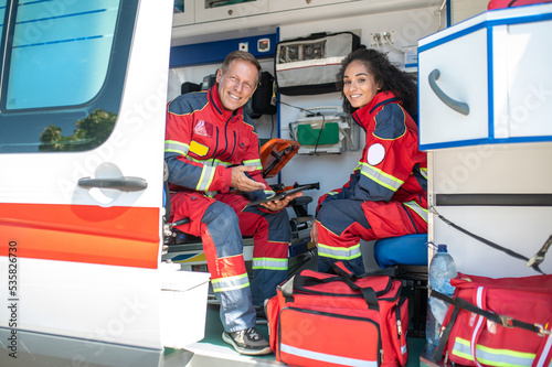 Εκτύπωση καμβά Cheerful paramedics posing for the camera in the ambulance car