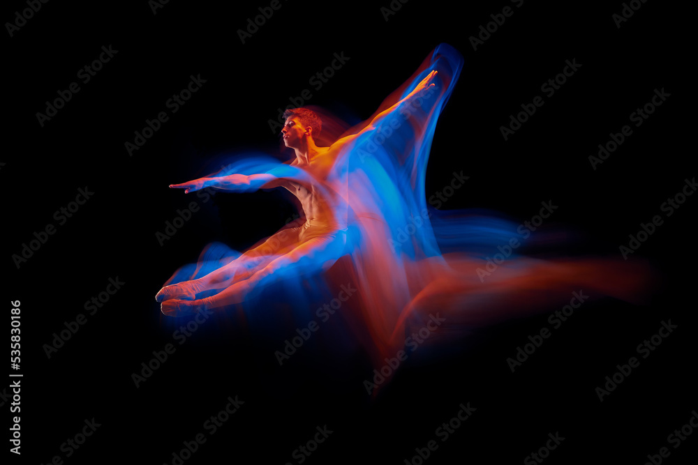 Aspiration. Solo performance of flexible male ballet dancer dancing isolated on dark background in glowing colorful neon light. Grace, art, beauty