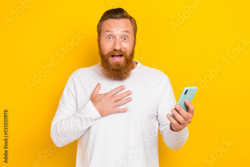 Portrait photo of young smiling shock crazy redhair man touch chest surprised million subscribers isolated on yellow color background