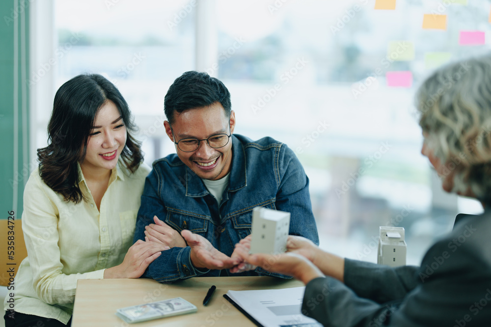 Guarantee Insurance Sign a contract, couple a smiling couple is signing a contract to invest in real estate with the Mortgage officer with the bank Guarantee Insurance Sign a contract, couple a smiling couple is signing a contract to invest in real estate with the Mortgage officer with the bank