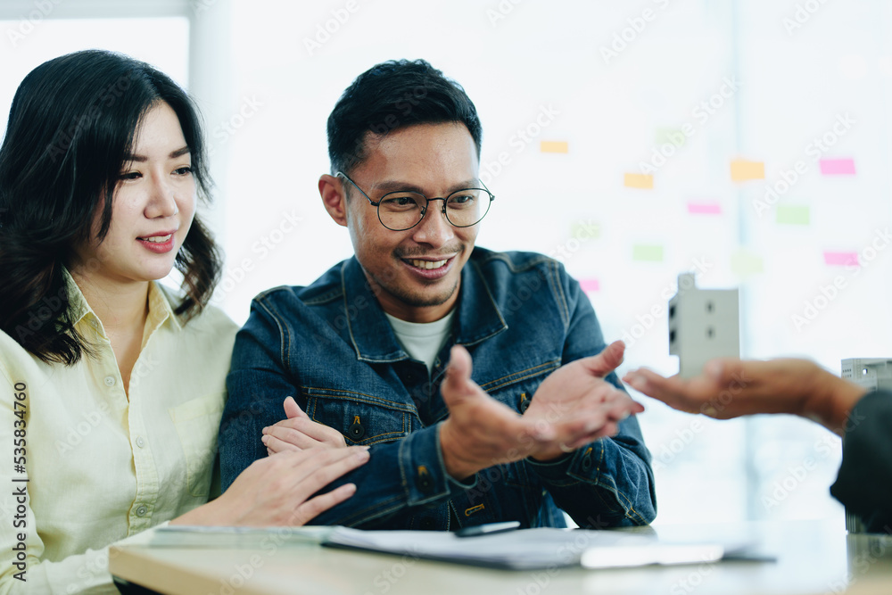 Fototapeta premium Guarantee Insurance Sign a contract, couple a smiling couple is signing a contract to invest in real estate with the Mortgage officer with the bank
