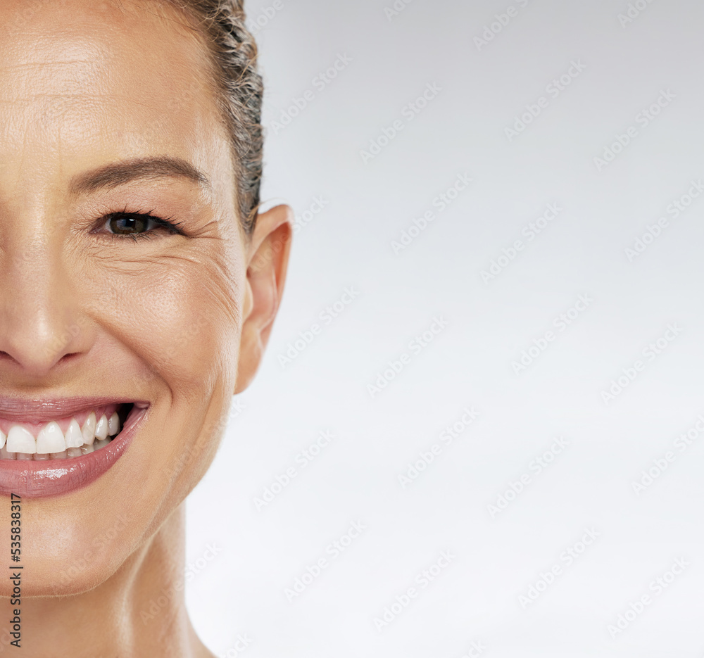 Half face, skincare and mature woman with smile for facial wellness in retirement against grey mockup studio background. Elderly model with beauty and skin health from dermatology with mock up space Half face, skincare and mature woman with smile for facial wellness in retirement against grey mockup studio background. Elderly model with beauty and skin health from dermatology with mock up space