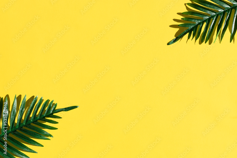 Minimal tropical green palm leaf on yellow paper background. Flat lay Top view with copy space for your text.