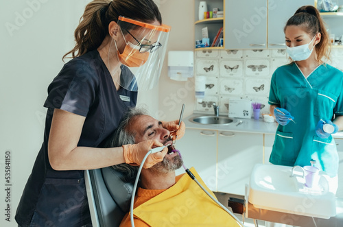 Tableau sur toile Handsome male patient sitting on a dentist's chair and getting dental restoratio