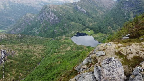 Revealing Leiro freshwater lake above Eidslandet in Vaksdal Norway - Beautiful aerial sliding out from behind massive cliff high up in the mountains photo