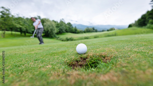 Golfer putting golf ball on the hole