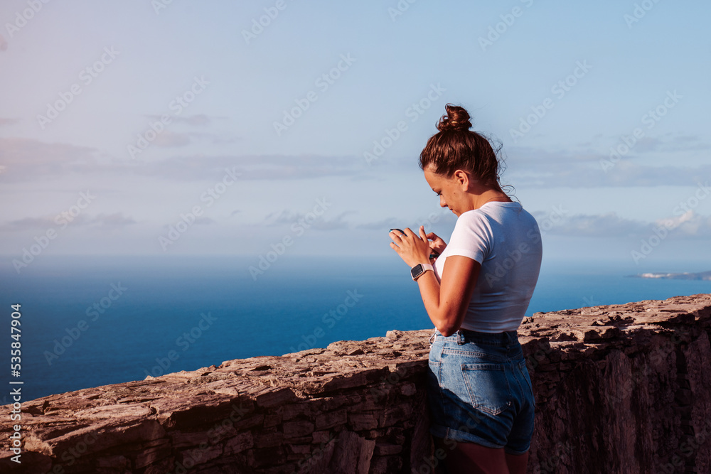 Digital nomad working on her phone while on a viewpoint