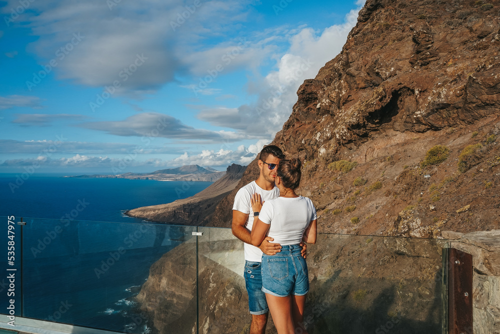 Couple on their honeymoon on a viewpoint against volcanic cliffs