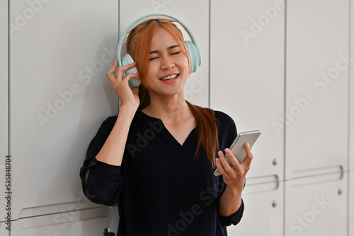 Young millennial woman wearing headphones enjoy music and sing along. photo