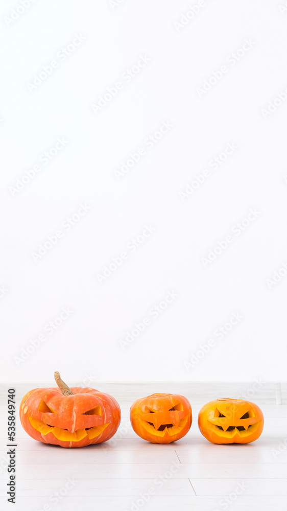 Jack-o-lantern carved pumpkin on light wall background with copy space, autumn and halloween home decor