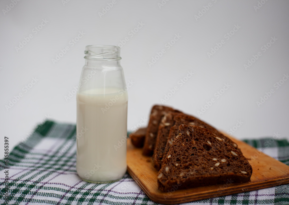 Slices of rye bread next to a bottle of milk on the kitchen table.