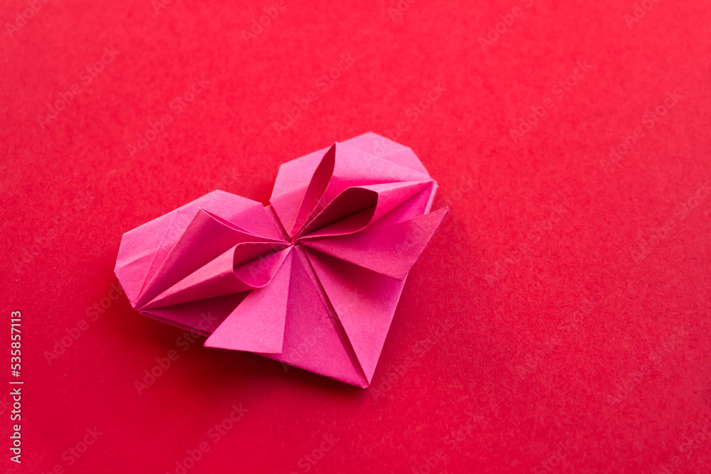 Pink paper heart origami isolated on a red background Pink paper heart origami isolated on a red background