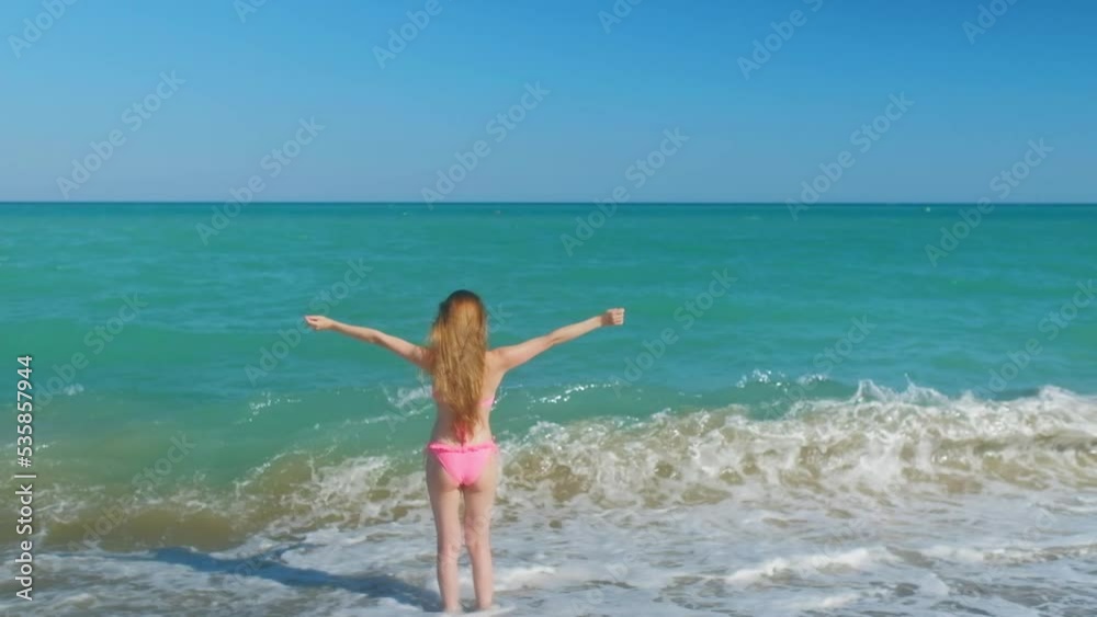 Tall woman with a long hair from a back is on a beach. Tall woman with a long hair from a back is on a beach.