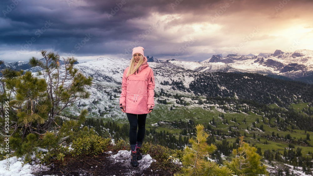 a woman on top of a mountain at sunset, in the first snow.