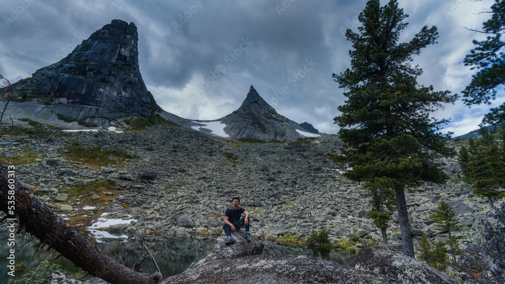 a man in the mountains is sitting on a rock. against the background of a parabolic mountain