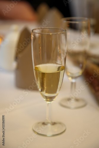 Ein halb gefülltes Glas mit Sekt auf einem Partytisch.