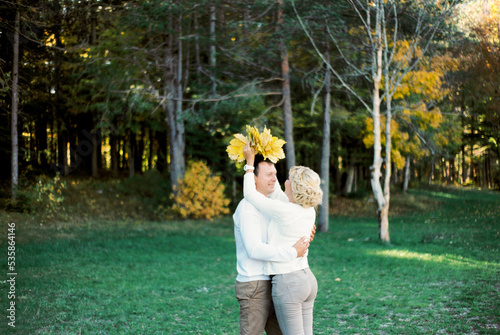 Woman puts a wreath of yellow leaves on the head of a man standing in the park