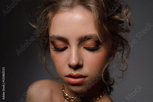 Young beauty with well-groomed eyebrows and professional make-up on a black background  close-up