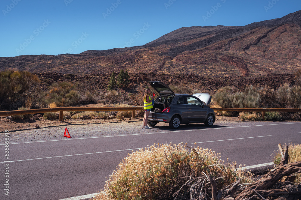 Woman calls car insurance by phone to try to solve her mechanical problem. The car stopped working.