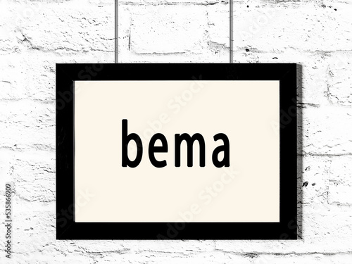 Black frame hanging on white brick wall with inscription bema photo