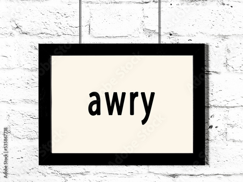 Black frame hanging on white brick wall with inscription awry