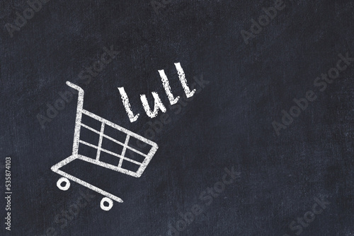 Chalk drawing of shopping cart and word lull on black chalboard. Concept of globalization and mass consuming photo