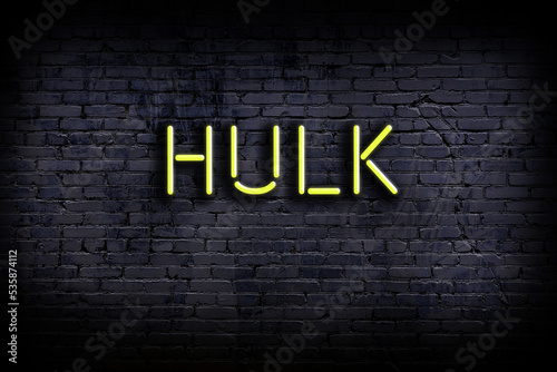 Neon sign. Word hulk against brick wall. Night view