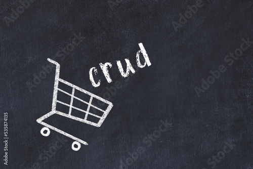 Chalk drawing of shopping cart and word crud on black chalboard. Concept of globalization and mass consuming photo
