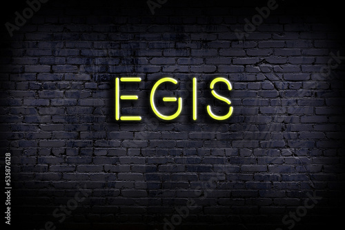 Neon sign. Word egis against brick wall. Night view