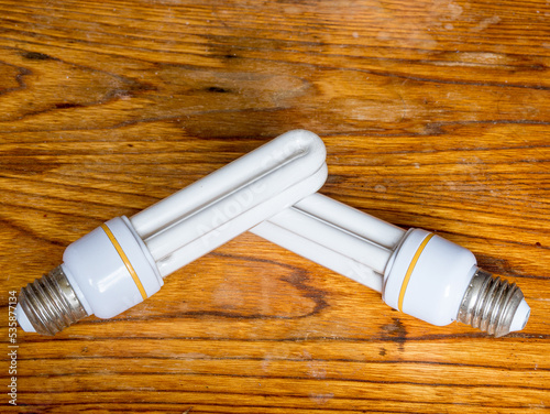 Two old energy-saving light bulbs on a wooden work table