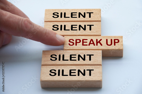 Finger pointing at wooden block with word speak up. Courage to speak up concept
